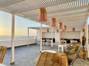 a patio with chairs and tables and the ocean at Hostel La Smala in Essaouira