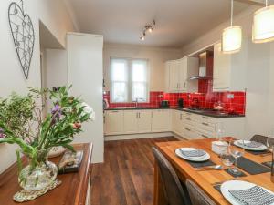 een keuken met een houten tafel en rode tegels bij Lonsdale Cottage in Carnforth