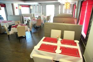 um restaurante com mesas brancas e cadeiras brancas e mesas vermelhas em Paravoor Galaxy Hotel em Cherai Beach
