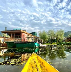 Green Paradise Houseboat - Centrally Heated في سريناغار: قارب اصفر في الماء امام مبنى