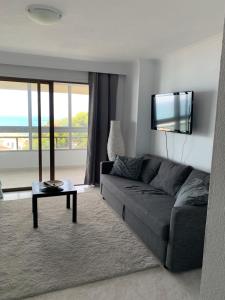 a living room with a couch and a flat screen tv at Piso bonito en la primera linea de la playa con vistas al mar en Benalmadena in Benalmádena