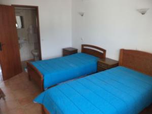 two beds in a room with blue sheets at Casa do João in Barão de São João