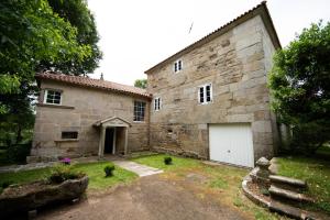 ein altes Steingebäude mit einer weißen Garage in der Unterkunft Pazo del siglo XVII en el corazón de Galicia in Lalín