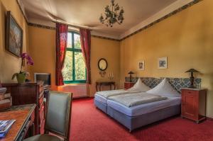 a bedroom with a bed and a desk and a window at Hotel zur Henne in Naumburg