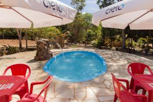 uma piscina com uma fonte e cadeiras vermelhas e um guarda-sol em Condomínio Shambala Piri em Pirenópolis