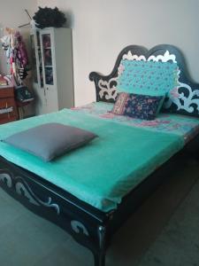 a bed with a green comforter and pillows on it at Furnished transient family room in Al 'Ayn