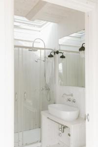 bagno bianco con doccia e lavandino di Trullo Piccolo ad Alberobello