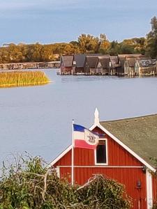 uma casa vermelha com um sinal em frente à água em Müritzblick am Wünnow em Röbel