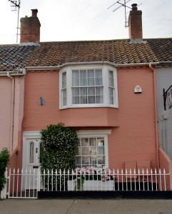 a pink house with a white fence in front of it at Oriel Cottage, Aldeburgh in Aldeburgh