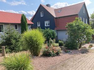 a house with a red roof and some bushes at Couple Appartement Pension Volgenandt in Breitenbach
