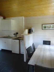 uma cozinha com uma mesa e cadeiras de madeira e uma mesa e uma mesa em Le Domaine du Cerf Blanc em Carentoir