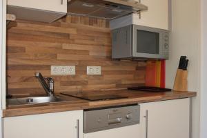 eine Küche mit einer Spüle und einer Mikrowelle in der Unterkunft Ferienwohnung K+M+B am Ossiacher See - Jerry in Bodensdorf
