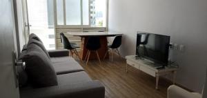uma sala de estar com um sofá, uma televisão e uma mesa em Apto 3 quartos Beira Mar Prox de Recife no Recife