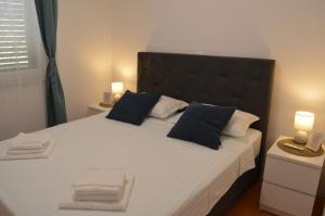 a bedroom with a large white bed with blue pillows at Holiday home Petra in Vinišće