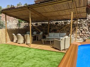 uma pérgola de madeira com cadeiras e uma piscina em Casa Juliana Turismo em Gabasa