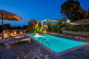 a pool in a backyard at night with an umbrella at Villa Fotini Kalivi in Raches in Skopelos Town