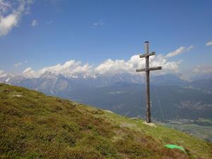 uma cruz de madeira no topo de uma colina com montanhas em Ferienwohnung Mariner Inzing em Inzing