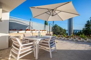 a table and chairs with an umbrella on a patio at Apartment Rippl in Crikvenica