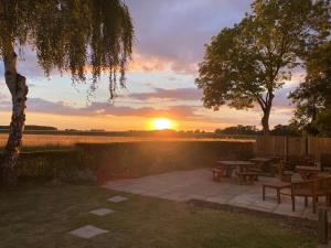 a sunset over a patio with tables and benches at Village Limits Bed and Breakfast Rooms in Woodhall Spa