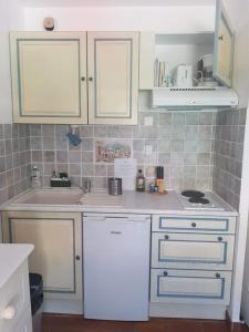 a kitchen with white cabinets and a sink at Studio Mag'Aline in Saint-Cyr-sur-Mer