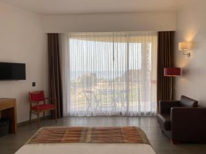 a bedroom with a large window with a chair and a couch at Foz Club - Algarve in Alvor