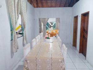 een eetkamer met een lange tafel met witte stoelen bij Salinas praia do atalaia in Salinópolis