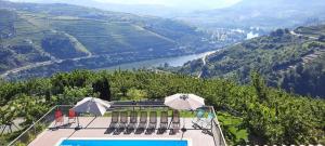 拉梅戈的住宿－Quinta do Pombal - Douro - Camila's，一座大楼的顶部,设有一座带椅子和遮阳伞的游泳池