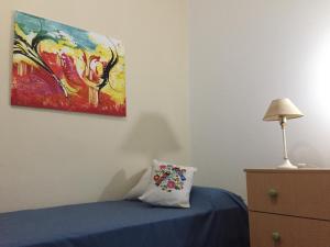 Un dormitorio con una cama azul y una pintura en la pared en Pompeya en Mar del Plata