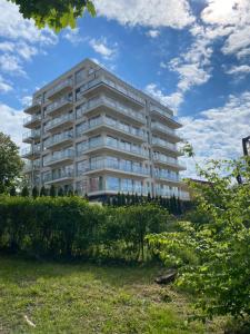 a tall white building with trees in front of it at Laurasapartment in Jarosławiec