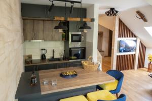 Zlatibor Apartman & Spa Casa Perfetta في زلاتيبور: مطبخ مع طاولة خشبية وكراسي زرقاء