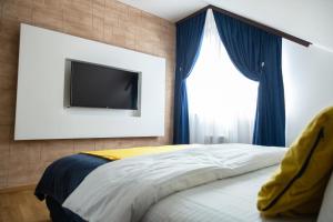 Cette chambre comprend un lit avec des rideaux bleus et une télévision. dans l'établissement Zlatibor Apartman & Spa Casa Perfetta, à Zlatibor