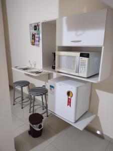 a kitchen with a microwave and a refrigerator at Hospedagem Elite térreo in Cunha
