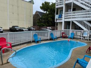 a small swimming pool with chairs and a building at Sea Palace Motel in Seaside Heights