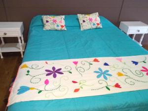 a bed with a blue blanket with flowers on it at Casa Patagónica Los Charitos in El Chalten