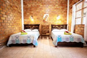 Habitación con 2 camas y pared de ladrillo en Huingos Eco Lodge en Tarapoto