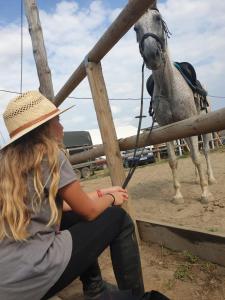 een vrouw met een paard achter een hek bij Hobby Land Ranch Horse's barn guesthouse in Găneasa