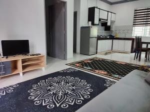 a room with a kitchen and a living room with a rug at Kayangan Inn in Rantau Panjang