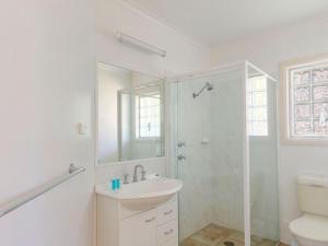 uma casa de banho branca com um lavatório e um chuveiro em Seachange Townhouse 4 em Hawks Nest