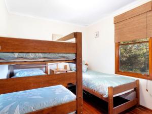 a bedroom with two bunk beds and a window at Gumtree Cottage Hawks Nest in Hawks Nest