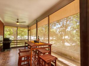 a screened porch with a wooden table and chairs and windows at Magic Moments in Tea Gardens