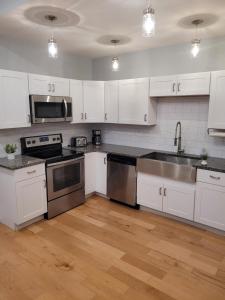 una cocina con armarios blancos y electrodomésticos de acero inoxidable en Cincy Dream! Walk to Zoo, UC, hospitals, and Short Vine district, en Cincinnati