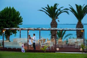 a man and a woman standing under a gazebo at Queens Bay Hotel in Paphos