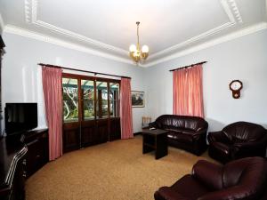 a living room with two leather chairs and a tv at The Lakes Cottage in Tea Gardens