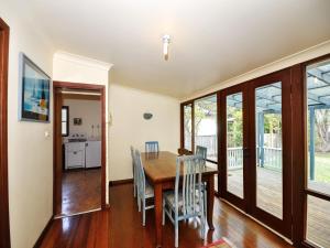 ein Esszimmer mit einem Holztisch und Stühlen in der Unterkunft The Lakes Cottage in Tea Gardens