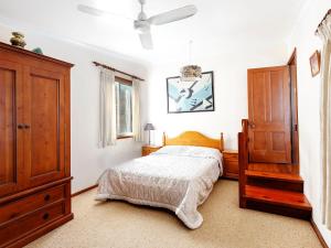 a bedroom with a bed and a dresser at The Lakes Cottage in Tea Gardens