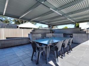 an outdoor patio with a blue table and chairs at Close To The Myall River Pet Welcome in Hawks Nest