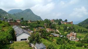 a village on a hill with mountains in the background at Unique Hotel and Lodge - Pleasure of Homely Stay - in Bandīpur