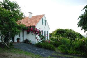 uma casa branca com flores ao lado dela em Casa do Areal em São Roque do Pico