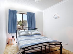 a bedroom with a bed with blue curtains and a window at 4 Rio Vista in Hawks Nest