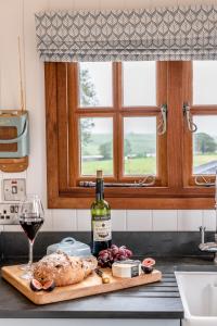 a bottle of wine sitting on a cutting board with a glass of wine at Daisy Park Shepherds Hut in Looe